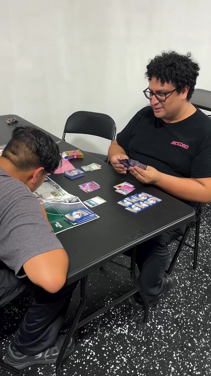 Two players enjoying a trading card game at a Rawmon Play Center table